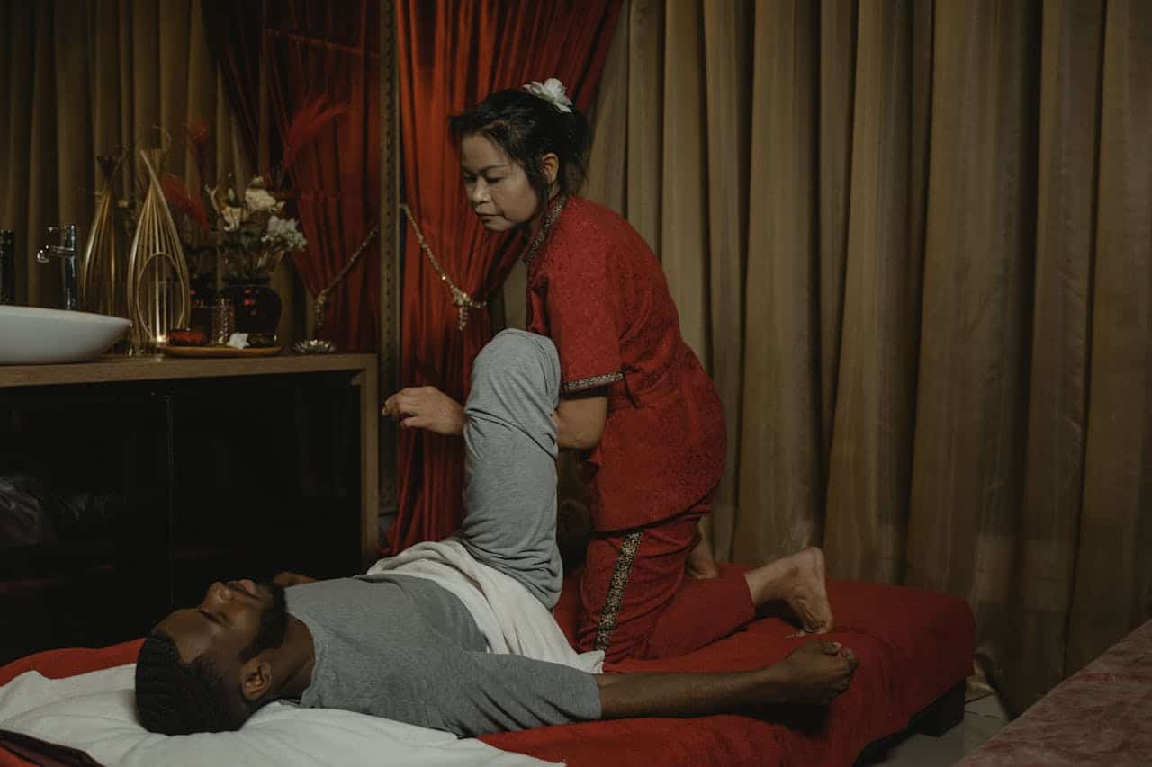 An adult man receiving a therapeutic massage from a professional masseuse in a calming indoor setting.